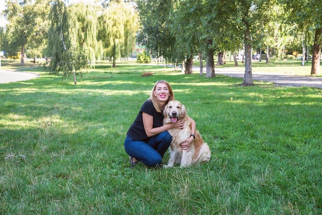 Mujer joven con su perro perdiguero en un parque de verano.