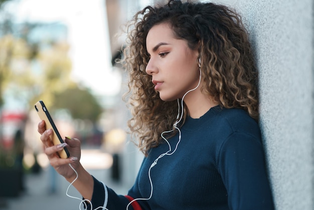 Mujer joven con su teléfono móvil al aire libre en la calle.