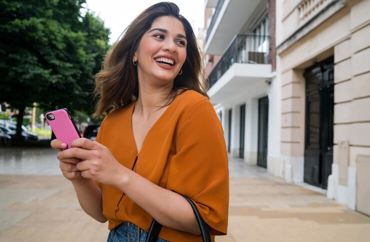Foto mujer joven con su teléfono móvil mientras está de pie al aire libre en la calle. concepto urbano y de comunicación.