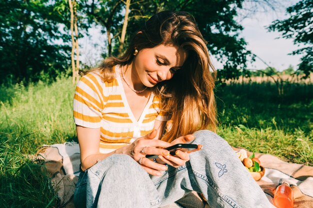 Mujer joven con su teléfono en un picnic al aire libre