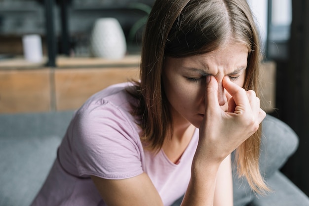 Foto mujer joven subrayada que sufre de dolor de cabeza que se sienta en casa