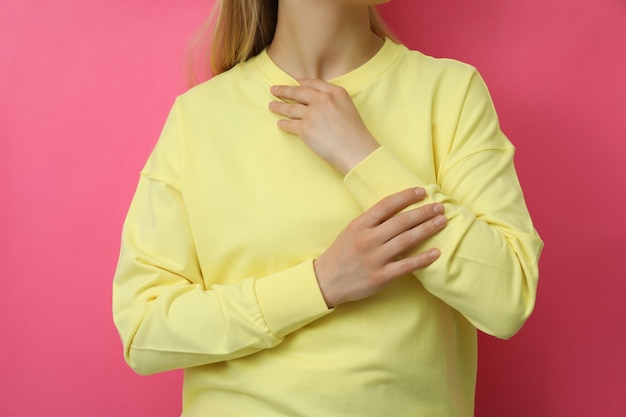 Foto mujer joven en sudadera amarilla contra rosa