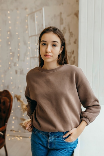 Foto mujer joven, en, sudadera con capucha, posar, en, estudio