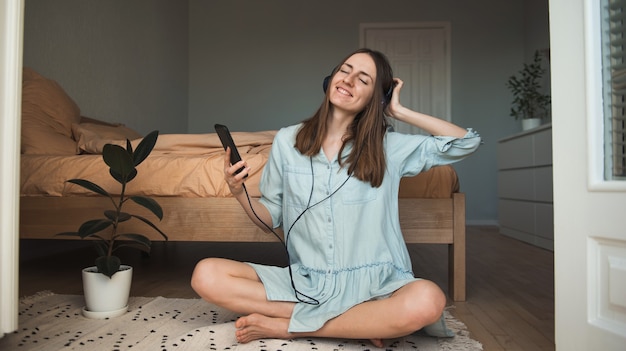 Foto mujer joven en el suelo escuchando música con los ojos cerrados