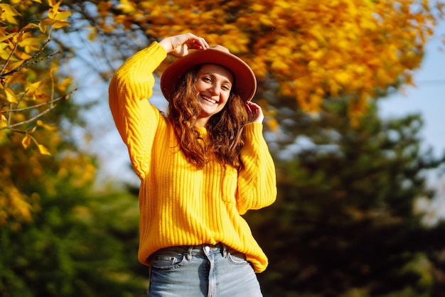 Mujer joven en un suéter amarillo y jeans descansando en la naturaleza Concepto de estilo de moda Estilo de vida de la gente