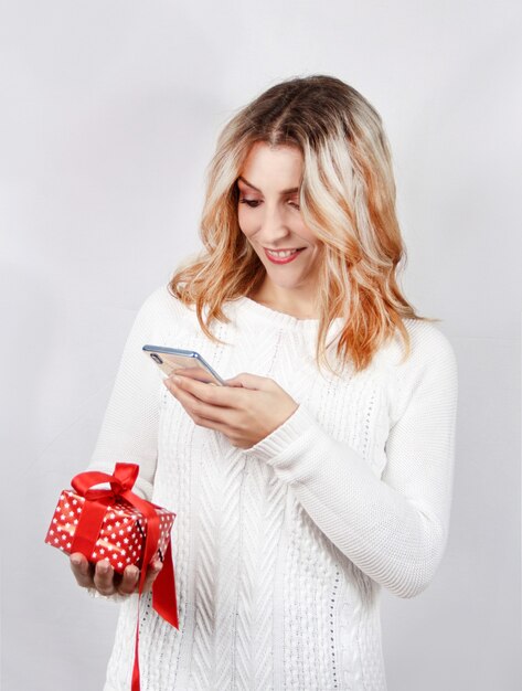 Mujer joven en suéter blanco tomando fotos del presente