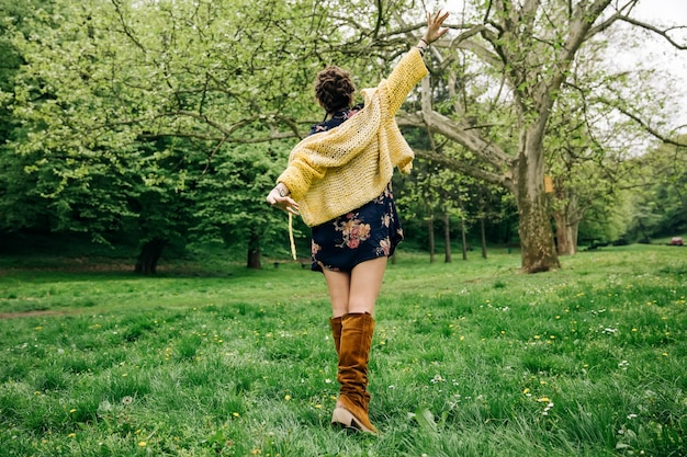 Mujer joven con suéter moderno y posando en el parque