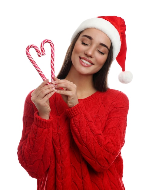 mujer joven, en, suéter rojo, y, santa sombrero, tenencia, bastones de caramelo, blanco, plano de fondo