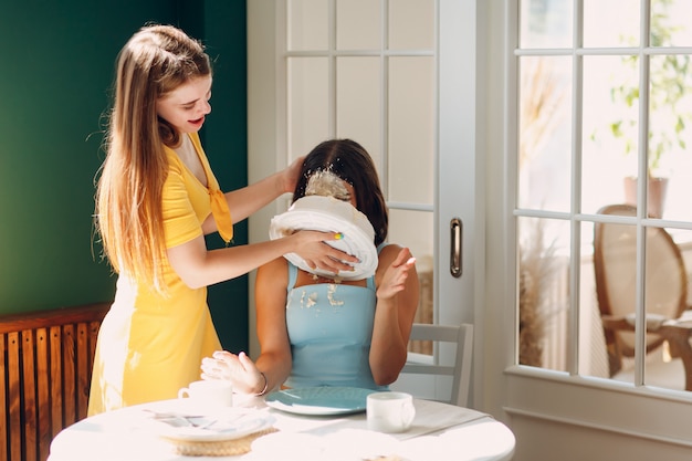 Mujer joven sumerge la cara en pastel blanco con crema. Concepto de feliz cumpleaños.