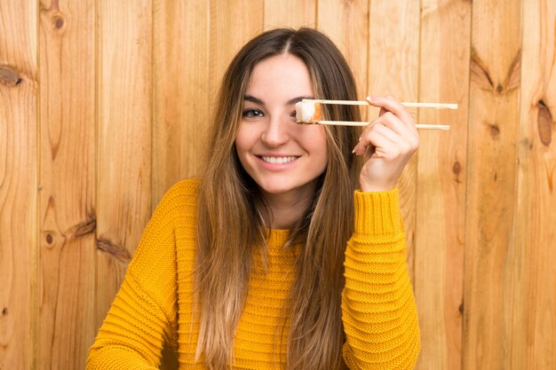 Foto mujer joven con sushi sobre fondo de madera