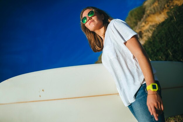 mujer joven, con, tabla de surf, posición, en la playa, mirar, ocaso