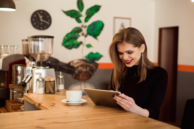 Mujer joven con tablet PC en un café.