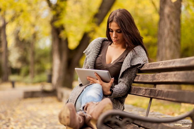 Foto mujer joven con tableta en el banco