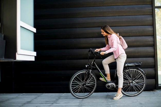 Mujer joven con tableta y bicicleta eléctrica al aire libre