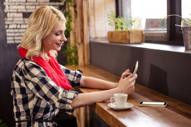 Mujer joven con tableta digital en cafetería