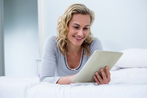 Mujer joven con tableta digital en cama