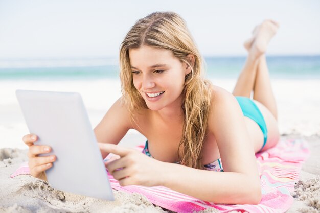 Mujer joven con tableta digital en la playa