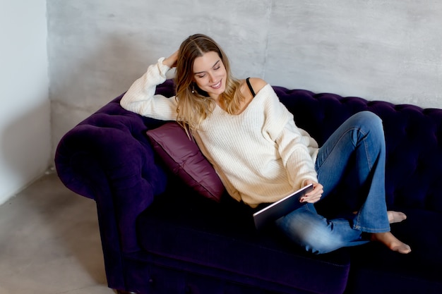 Foto mujer joven con tableta digital en el sofá