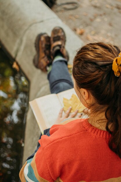 Foto mujer joven de talla plus leyendo un libro en otoño parque de otoño en las luces del sol cuerpo diversidad positiva cuerpo