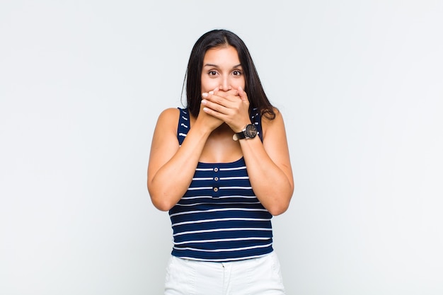 Foto mujer joven tapándose la boca con las manos con una expresión de sorpresa y sorpresa, manteniendo un secreto o diciendo ¡ups!