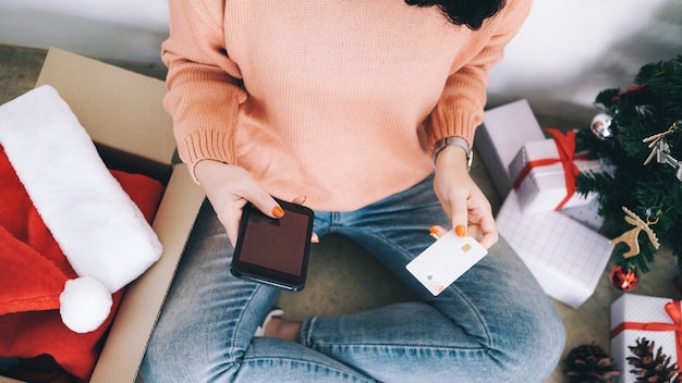 Mujer joven con tarjeta de crédito y haciendo compras en línea.