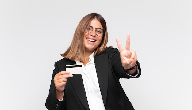 Mujer joven con una tarjeta de crédito sonriendo y mirando amigable