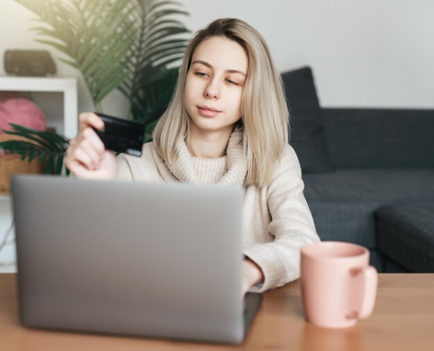 Mujer joven con tarjeta de crédito y usando computadora portátil Chica trabajando en línea Compras en línea banca por Internet trabajando desde casa