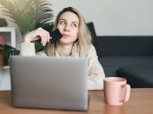 Mujer joven con tarjeta de crédito y usando una computadora portátil