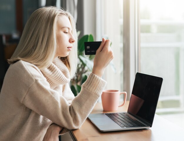 Mujer joven con tarjeta de crédito y usando la computadora portátil