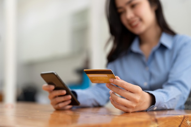Mujer joven con tarjeta de crédito y usando un teléfono inteligente para compras en línea Concepto de compra de pago en línea