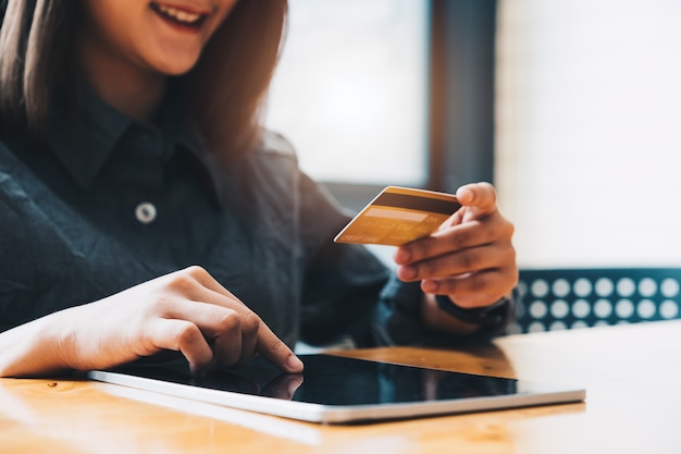 Mujer joven con tarjeta de crédito y uso de tableta. Concepto de compra online.