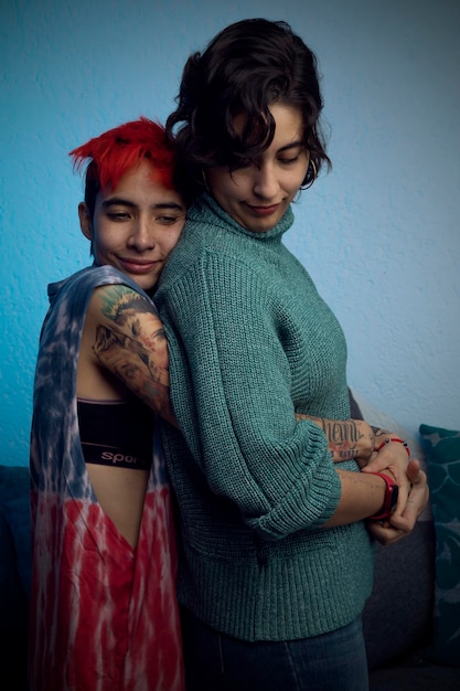 Mujer joven con tatuajes abraza a su pareja por detrás en un momento romántico