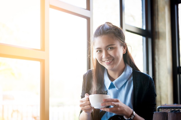 Mujer joven con taza de café en café