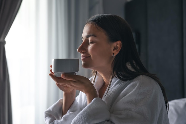 Una mujer joven con una taza de café en la cama