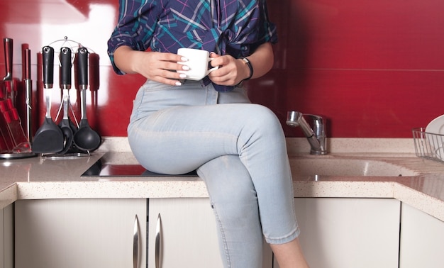 Mujer joven con una taza de café en la cocina.