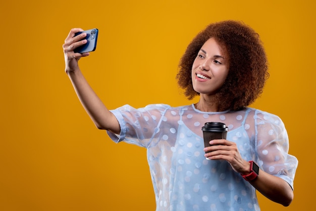 Mujer joven con una taza de café haciendo selfie