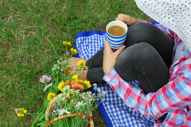 Mujer joven, con, taza de café, sentado, en, pradera, aire libre