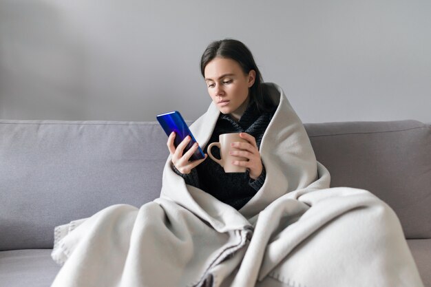 Mujer joven con taza y smartphone