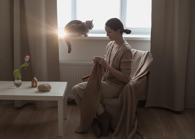 Mujer joven tejiendo en una habitación acogedora en casa