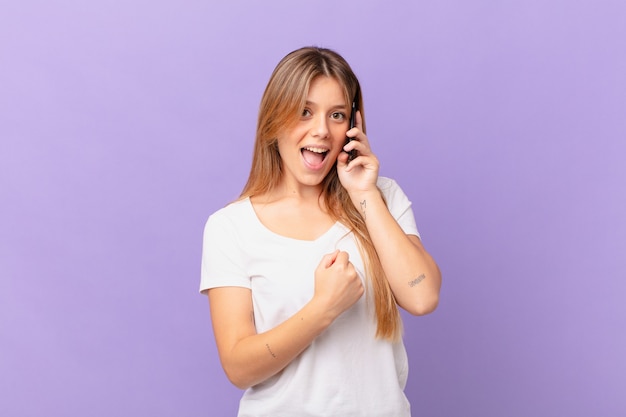 Mujer joven con un teléfono celular sintiéndose feliz y enfrentando un desafío o celebrando