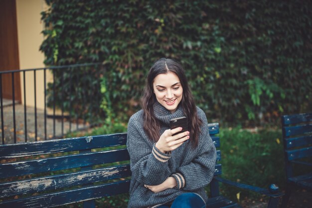 Mujer joven con un teléfono inteligente al aire libre sonriendo