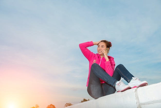 Mujer joven con un teléfono inteligente al atardecer.