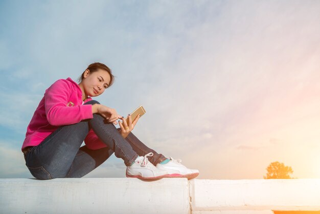 Mujer joven con un teléfono inteligente al atardecer.