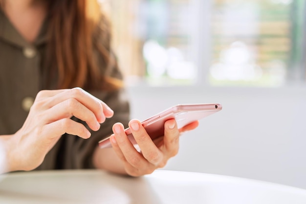 Mujer joven con teléfono inteligente y relajarse en la cafetería, estilo de vida moderno