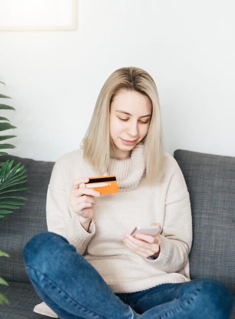 Mujer joven con teléfono inteligente y tarjeta de crédito bancaria