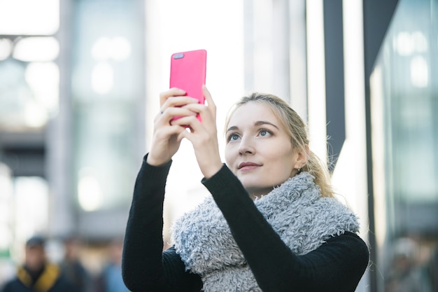 Mujer joven con teléfono inteligente y tomar fotos y usar aplicaciones