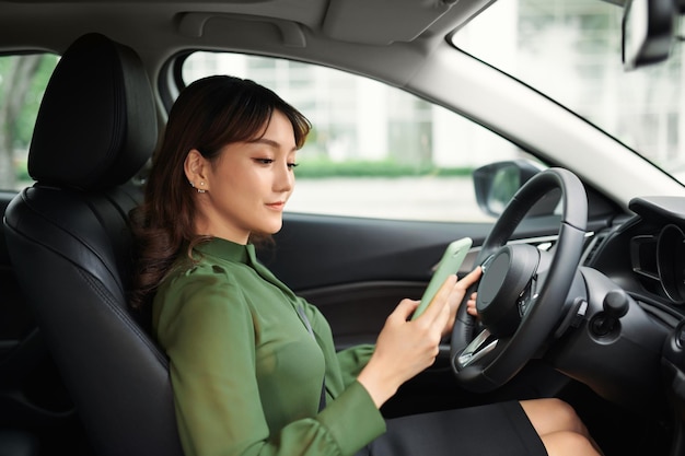 Mujer joven con teléfono móvil sentada en el coche