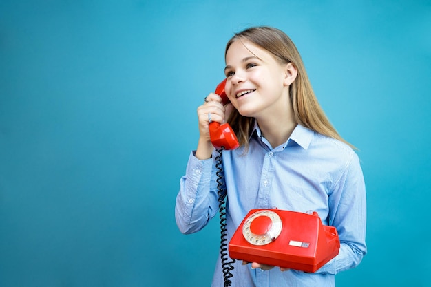 Mujer joven con un teléfono retro rojo en sus manos