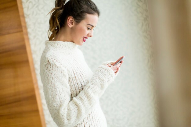 Mujer joven con telefono por ventana