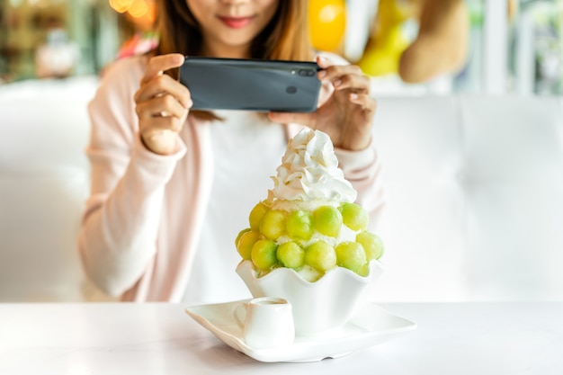 Mujer joven con teléfonos inteligentes para tomar fotos en un restaurante